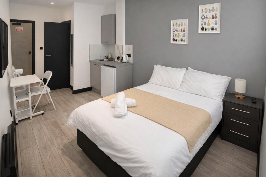 a bedroom with a large bed and a kitchen at 12 London Deluxe Studios in Streatham Vale