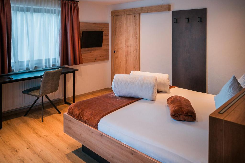 una camera da letto con un letto con una scrivania e una sedia di die Harmonie a Nauders