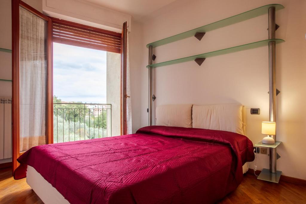 ein Schlafzimmer mit einem roten Bett mit einem großen Fenster in der Unterkunft Centrale con panorama. in Siena