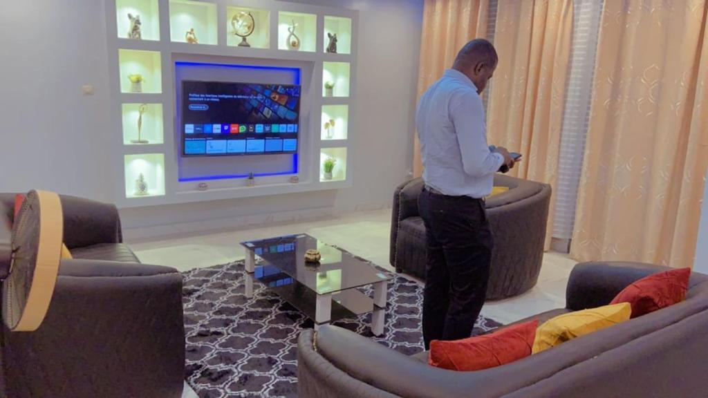a man standing in a living room playing a video game at Apparemment 2 chambres- Lemba Salongo in Kinshasa