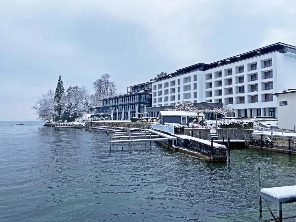 een groot gebouw naast een waterlichaam bij Campus Hotel Hertenstein in Weggis