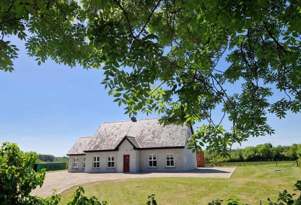 a white house with a red door in a field at The Lake House, cong in Cong