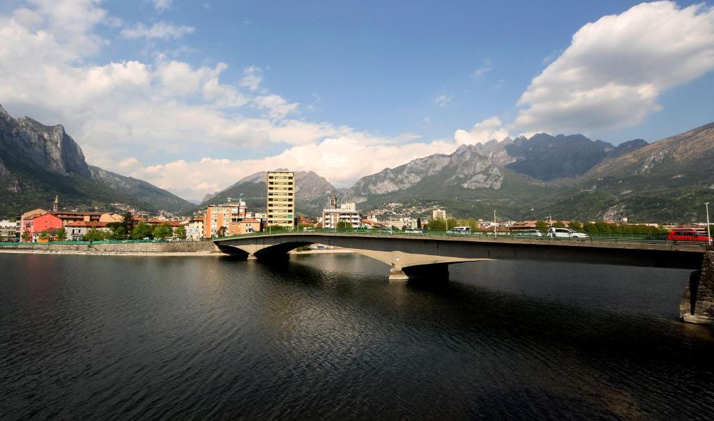 un ponte sopra un fiume con una città e montagne di Suite sogni di lago Lecco, Como a Malgrate