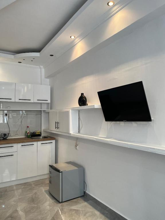a kitchen with white cabinets and a flat screen tv on the wall at Casa Luna Luxury Apartment in Nea Moudania