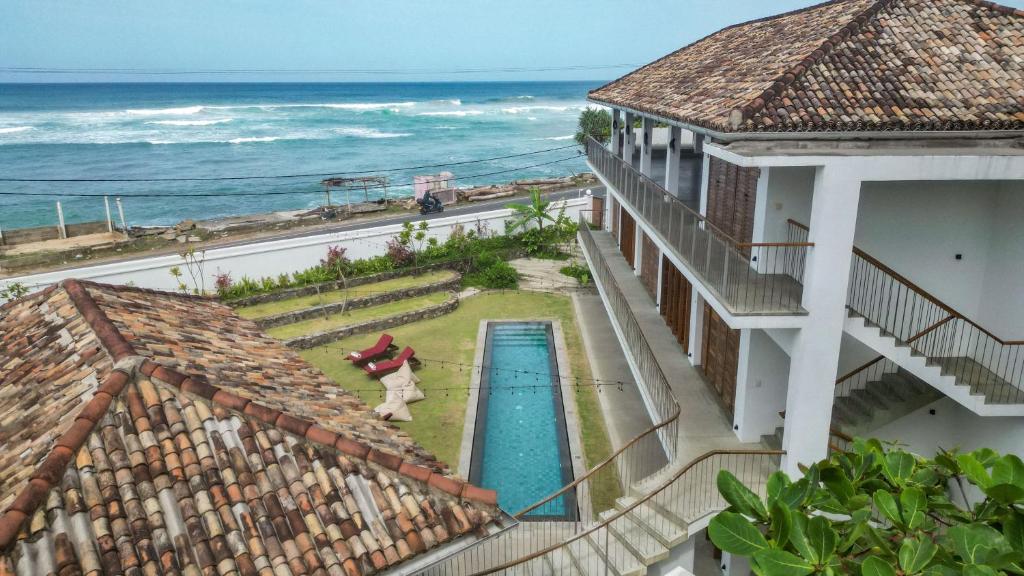 an aerial view of a building with a swimming pool and the ocean at UNU Boutique Hotel -- Adults Only -- in Ahangama
