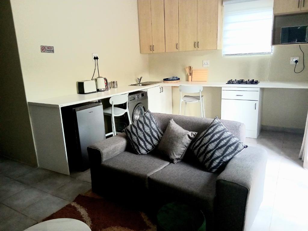 a living room with a couch and a kitchen at The Corner Nest in Roodepoort