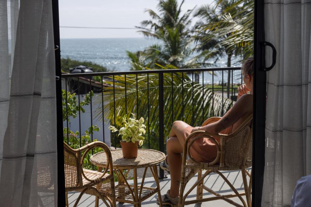 a woman sitting in a chair on a balcony at Surftunnel Beach Resort in Weligama