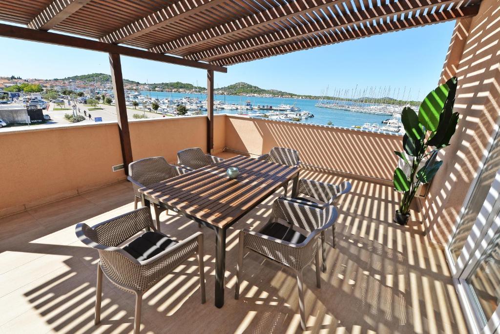 een tafel en stoelen op een balkon met uitzicht op de oceaan bij EnVi Apartments in Murter