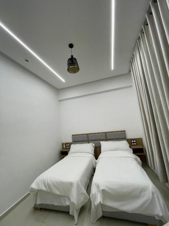 two beds in a room with white walls at Hôtel kairouan in Fez