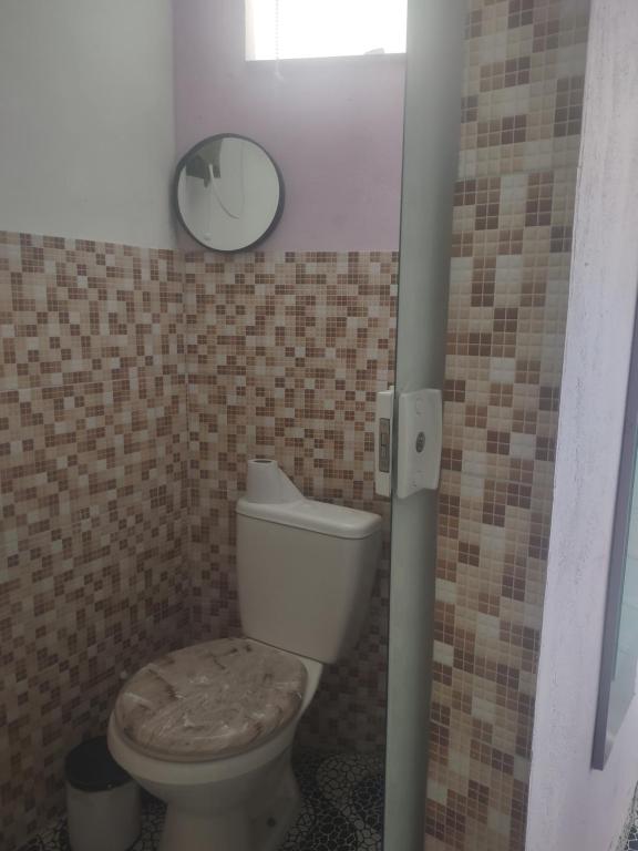 a bathroom with a toilet and a mirror in it at Espaço em Pero hospedagem in Cabo Frio