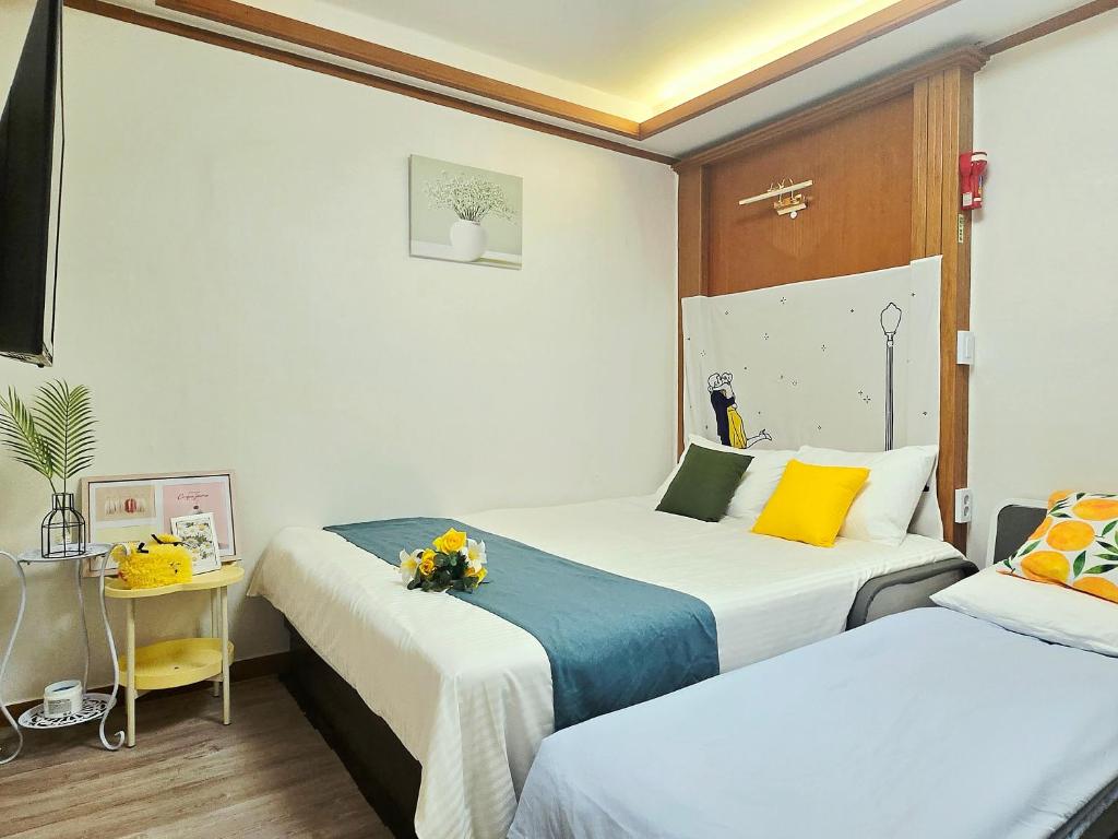 a room with two beds and a table with flowers at Bokman stay 01 in Seoul