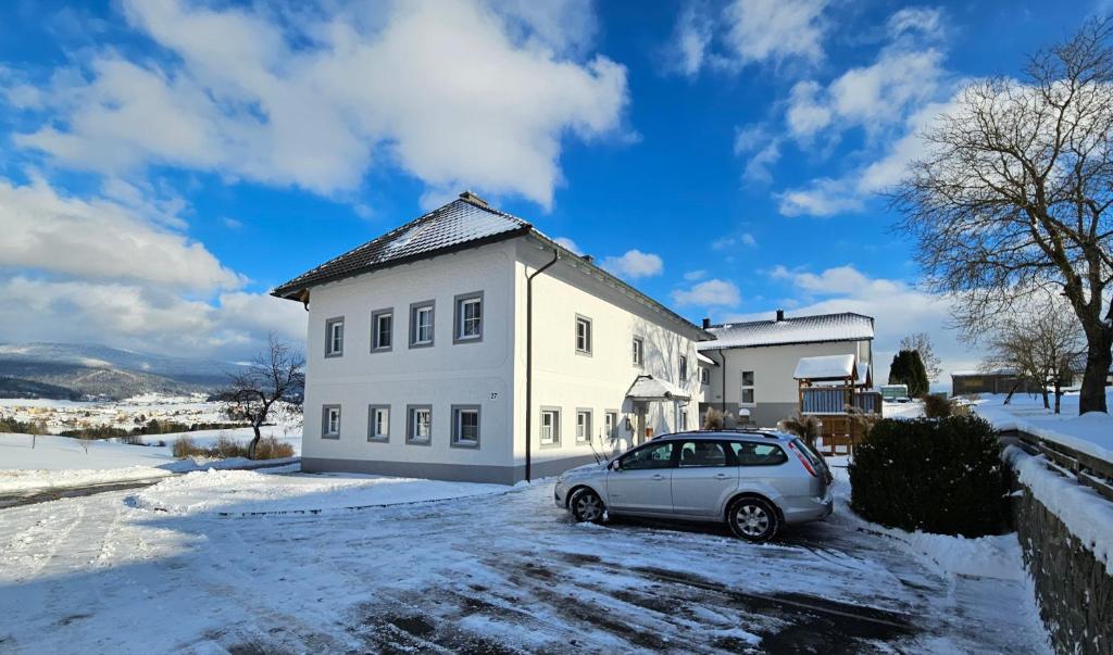 un'auto parcheggiata di fronte a una casa bianca di HOCHFICHTBLICK Apartments a Ulrichsberg