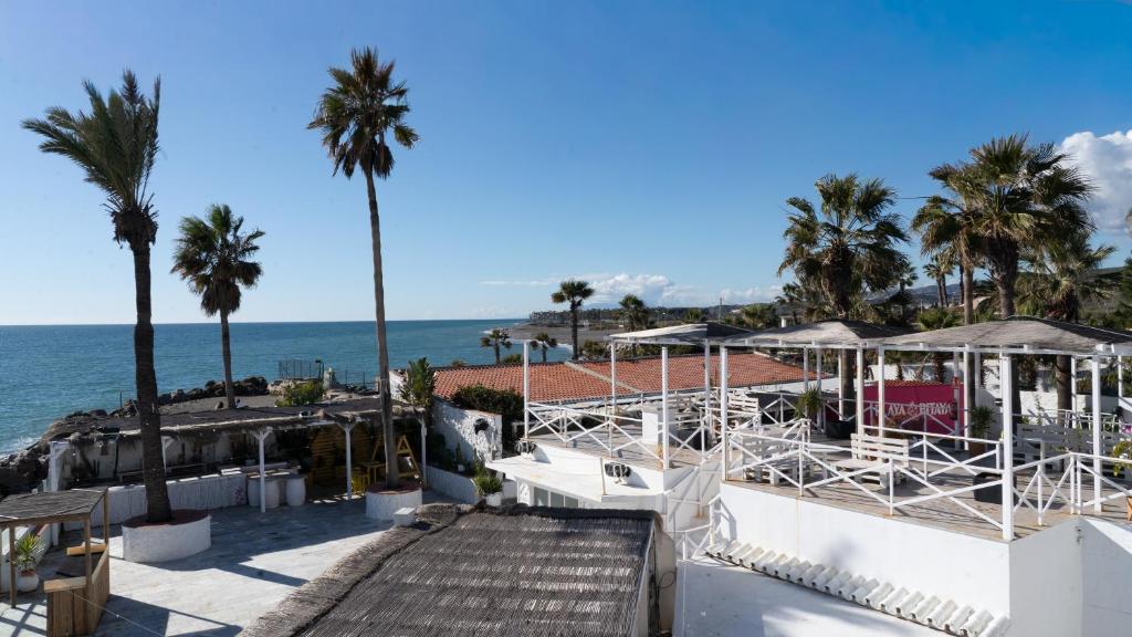 a view of the ocean from a resort with palm trees at Hostal Playa Pitaya in Torre del Mar
