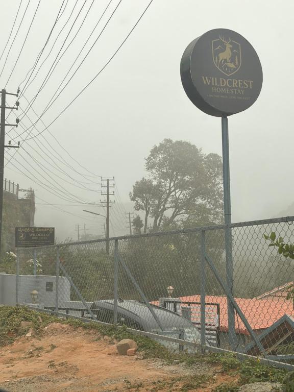 a sign on a fence next to a building at Wildcrest Homestay in Madikeri