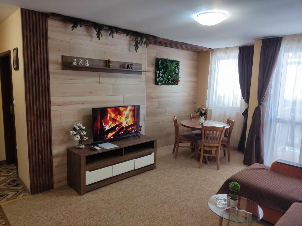 a living room with a couch and a tv and a table at Апартамент почивка в планината in Pamporovo