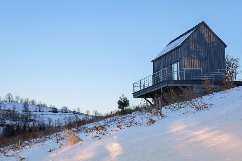 ein Holzhaus auf einem schneebedeckten Hügel in der Unterkunft Bliżej Nieba in Skrzydlna