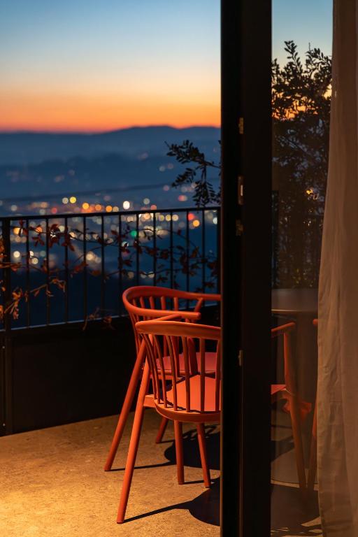 a red chair sitting on top of a balcony at El Cielo - Rooms with Panoramic View & El Carnicero Restaurant in Cornedo Vicentino
