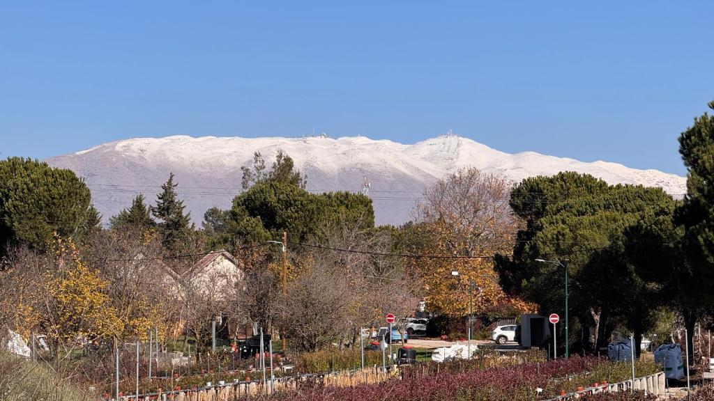 een met sneeuw bedekte berg in de verte met een straat bij Gal Ba'Har גל בהר in El-Rom