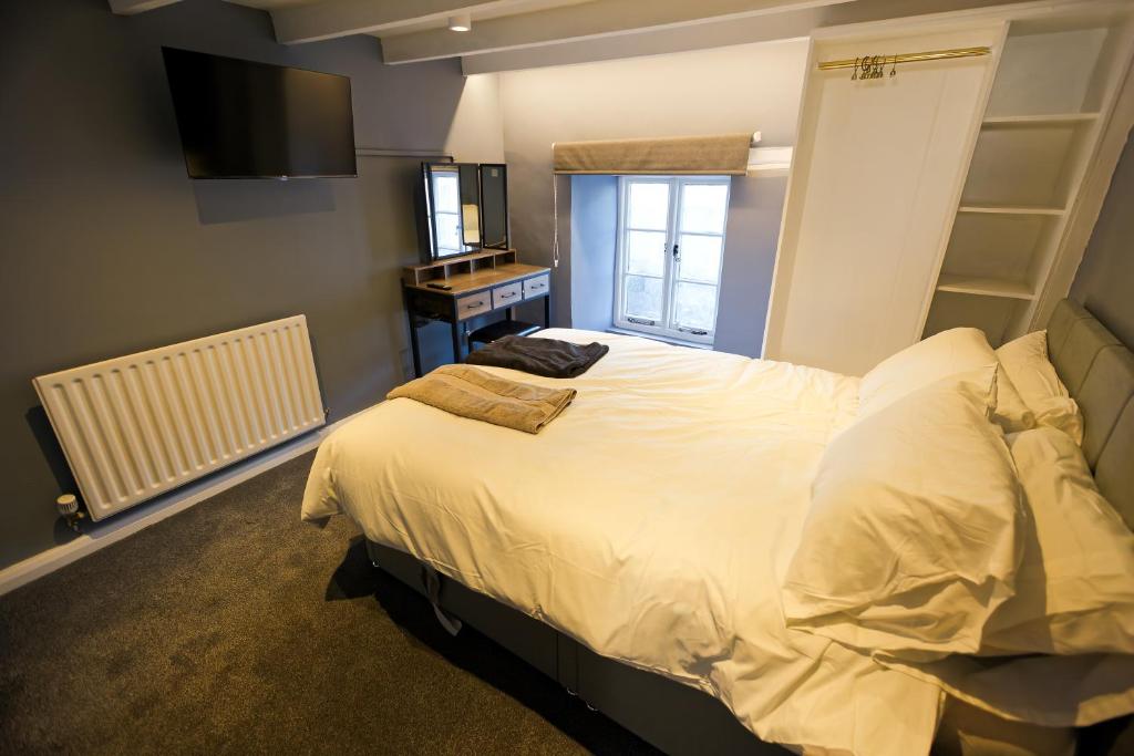 a bedroom with a large bed and a television at Monk and Tipster in Towcester