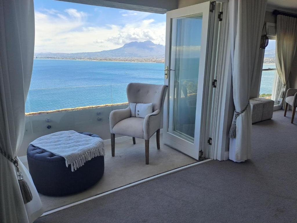 a room with a chair and a view of the ocean at Boutique Inn - Serenity in Gordonʼs Bay