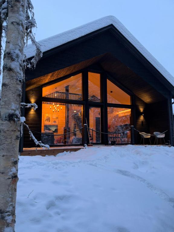een huis met een groot glazen raam in de sneeuw bij Villa Syli in Äkäslompolo