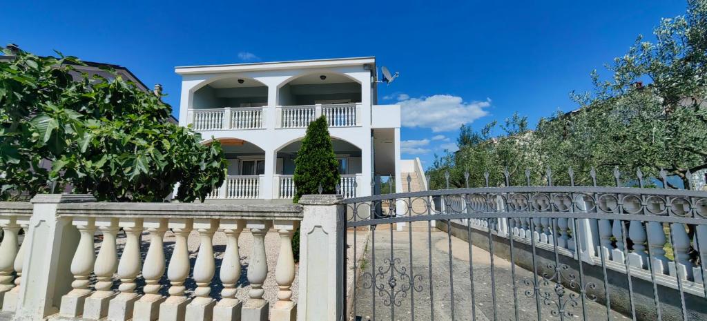 a white fence in front of a white house at Apartments Villa Granda Tolic in Biograd na Moru