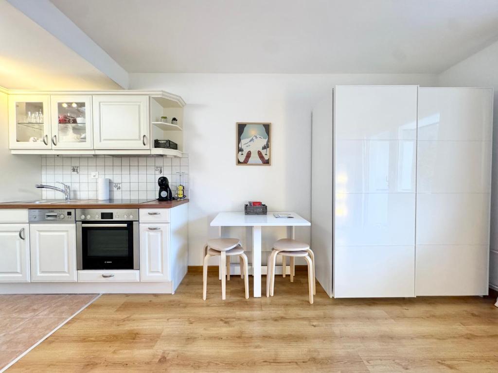 a kitchen with white cabinets and a table and chairs at Bellavista Morgins in Troistorrents