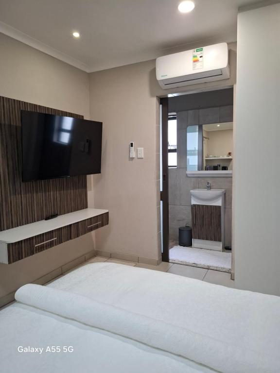 a bedroom with a bed with a flat screen tv on the wall at Petron home in Kempton Park
