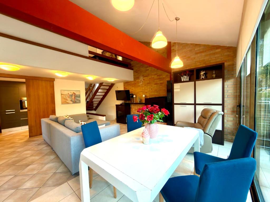 ein Wohnzimmer mit einem weißen Tisch und blauen Stühlen in der Unterkunft Villa Pineta Grande in Lignano Sabbiadoro