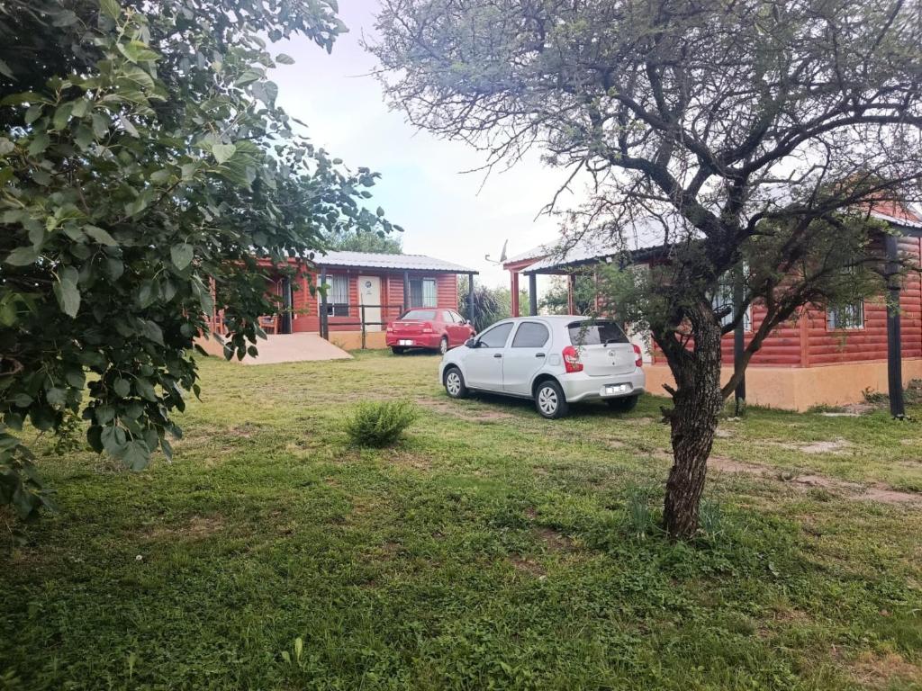 een witte auto geparkeerd in een tuin naast een boom bij Cabañas a 5 minutos del río in Alta Gracia