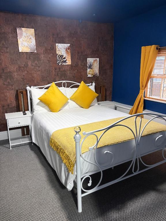 a bedroom with a large bed with yellow pillows at The Black Swan Inn in Leominster