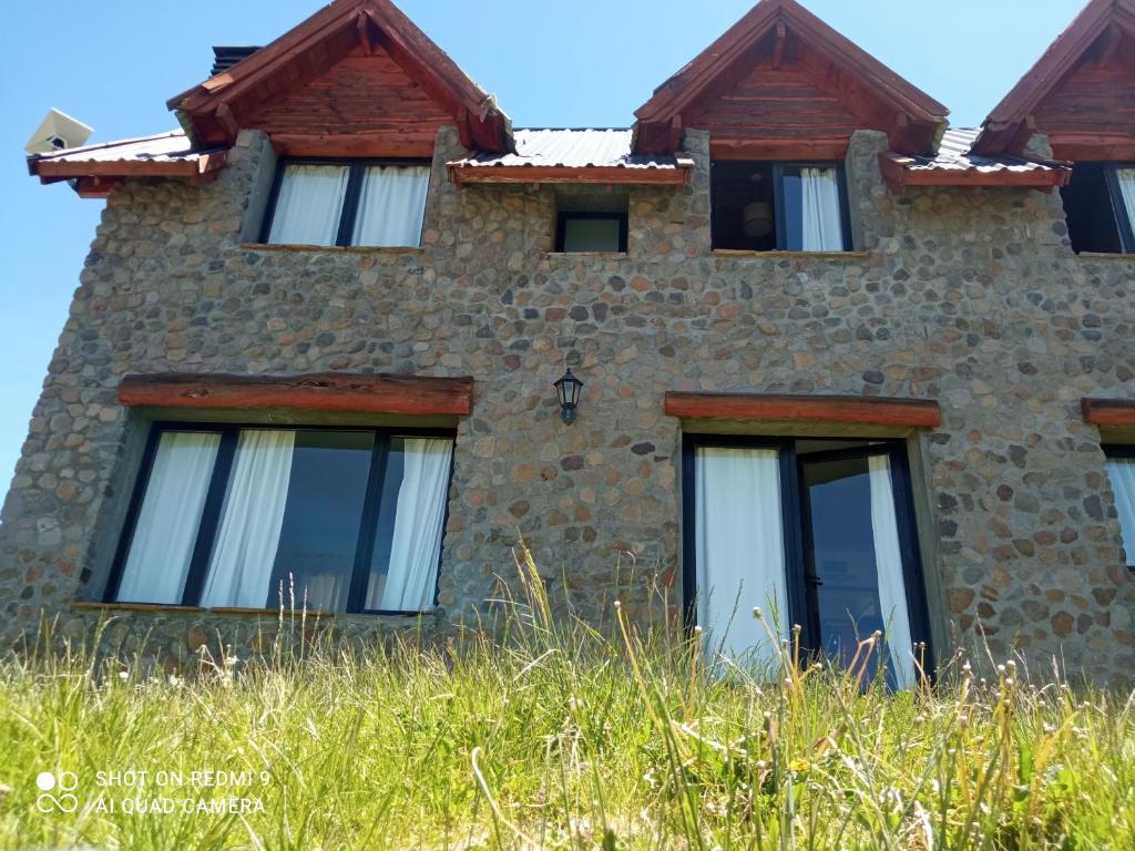 an old stone building with windows and grass at Patagonia Adriano in Caviahue