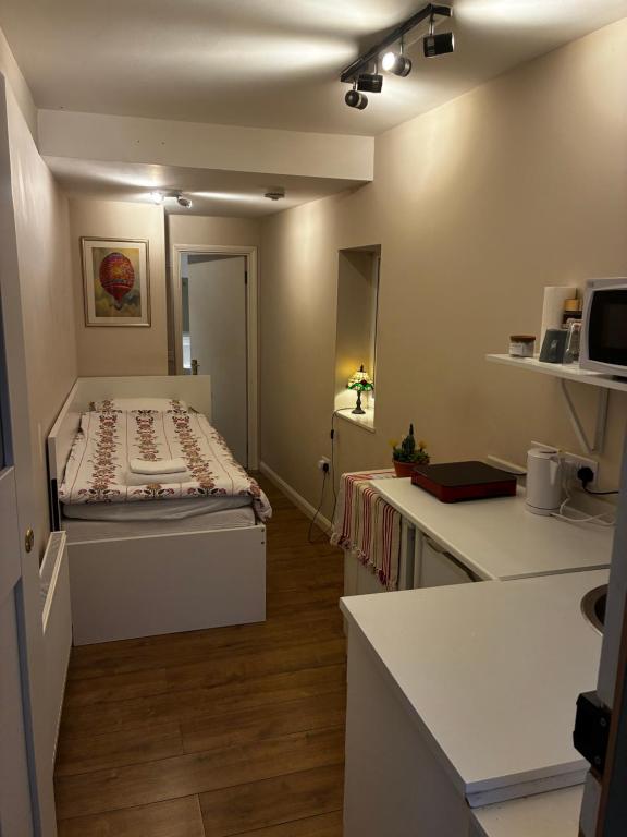 a small room with a bed and a kitchen at The Cozy Nook in Hanwell