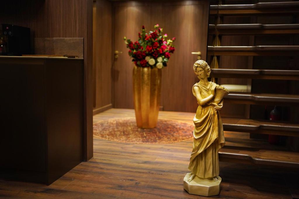 una statua di una donna in piedi accanto a un vaso di fiori di The HH Point a Tirana