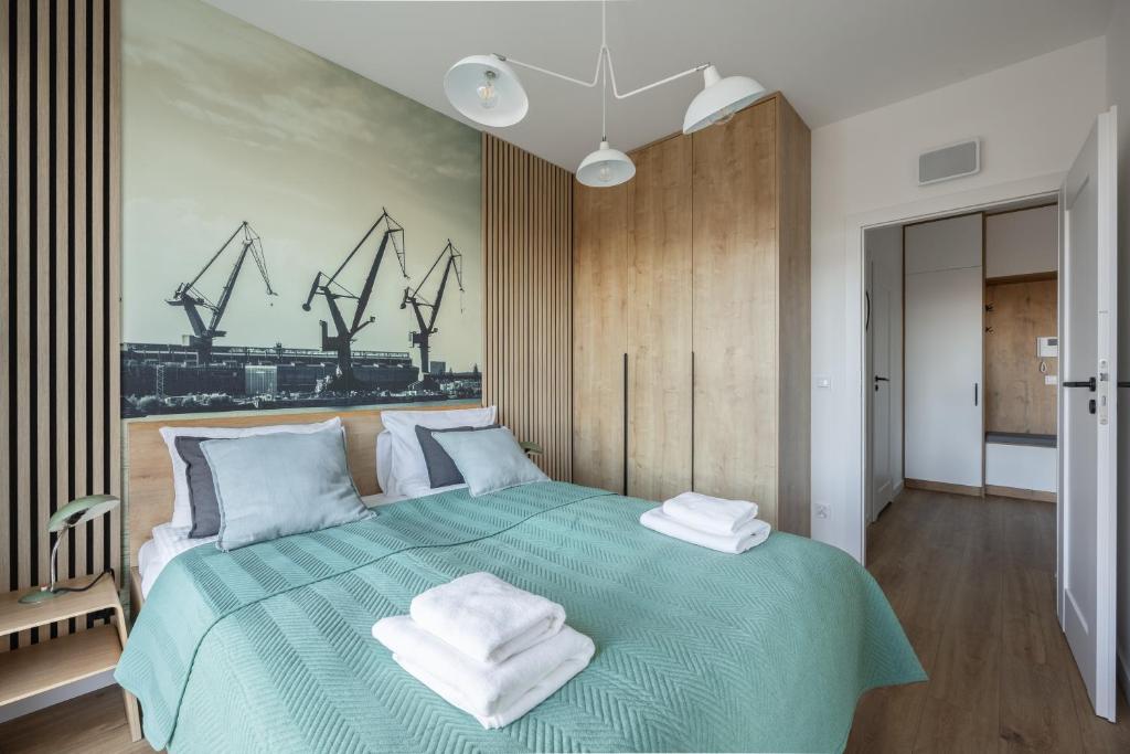 a bedroom with a green bed with towels on it at LILY APART - Foodhall & Rooftop Terrace in Gdańsk