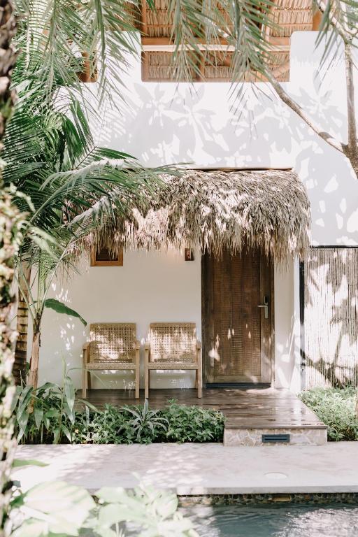 a house with two benches in front of a building at The Nomadic Hotel in Nosara
