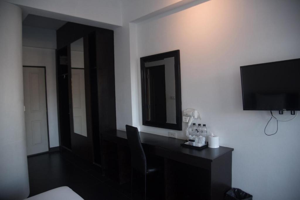 A compact in-room desk beneath a mirror, with refreshments and a television nearby.