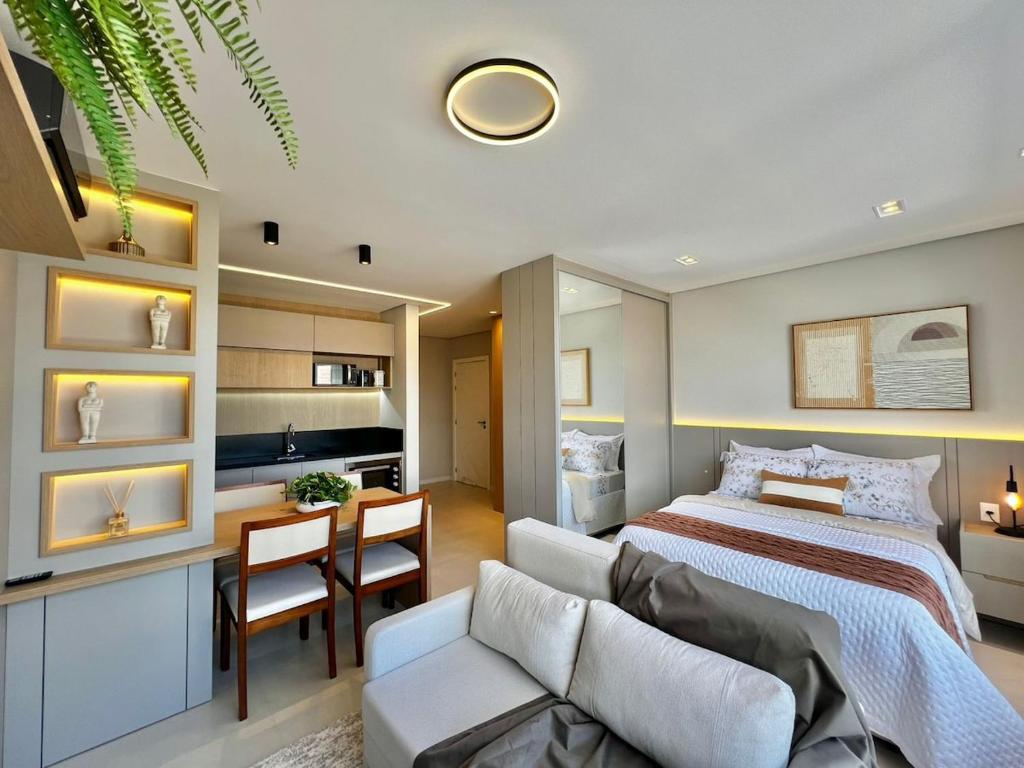 a bedroom with a bed and a living room at Studio Capão - novo com piscina e rooftop in Capão da Canoa