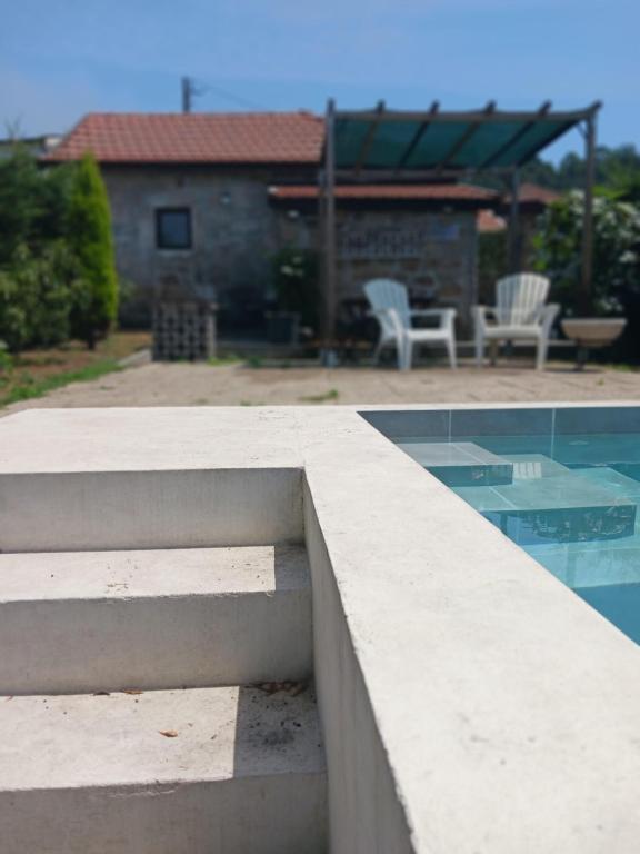 a view of a swimming pool with chairs and a house at Casa da Figueira in Guilhufe