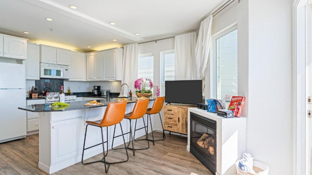 a kitchen with white cabinets and a counter with a fireplace at 2 Coastal Studios at Cayucus Beach Access Ocean Views in Cayucos