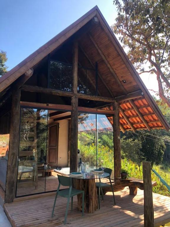 a cabin with a table and chairs on a deck at Chalé Casa da Pedra in Cunha