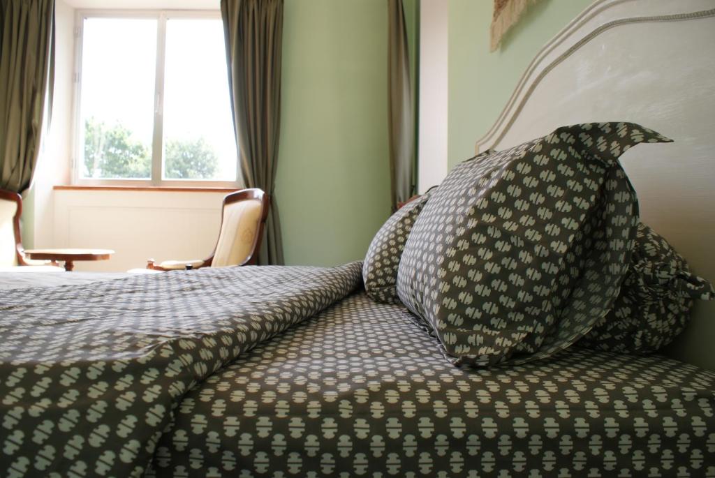 Schlafzimmer mit einem Bett mit einem Kissen und einem Fenster in der Unterkunft Les voisins de l'illet in Ercé-près-Liffré