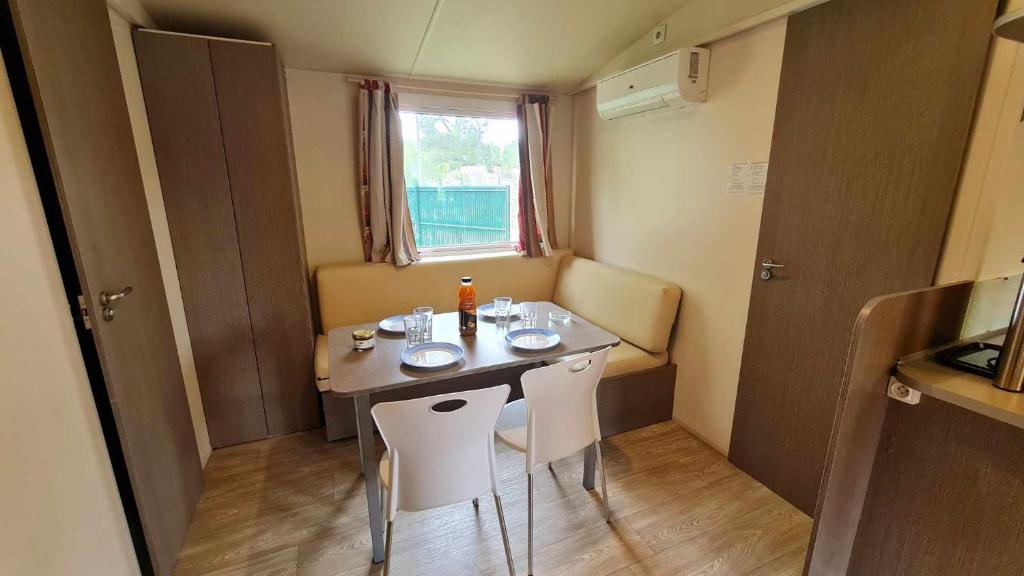 Cette petite chambre comprend une table et des chaises blanches. dans l'établissement Mobil Home au calme Camping 4 Cadenet, à Cadenet