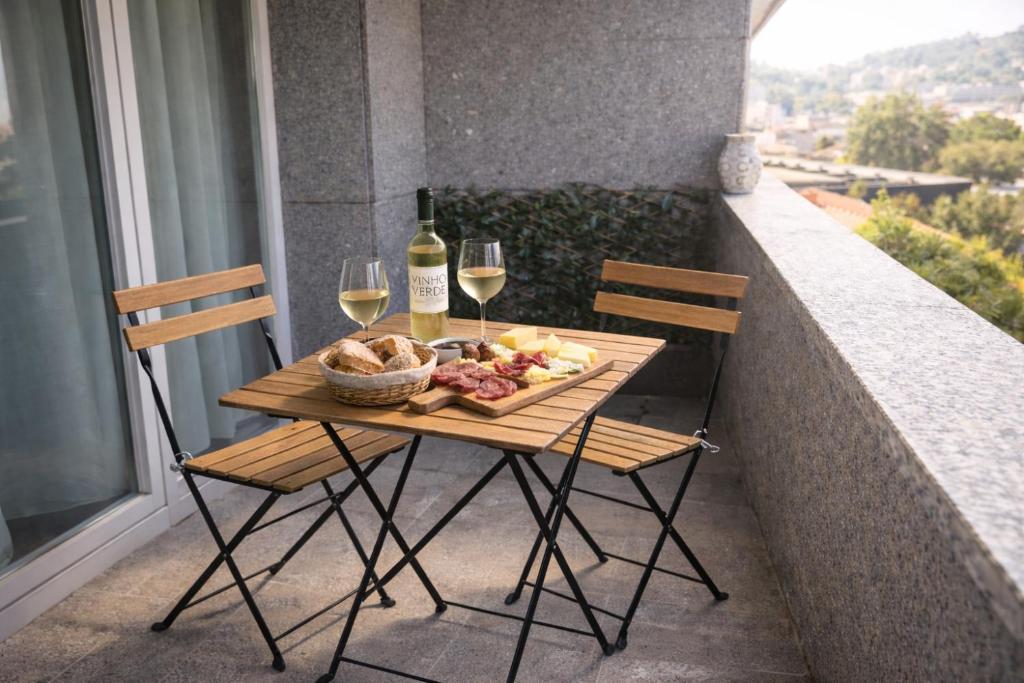 a table with two chairs and a plate of food and wine at Apartamento Centro Guimarães com Vista Panorâmica in Creixomil