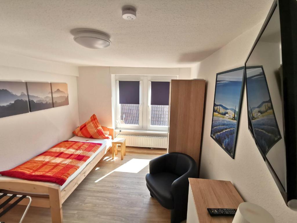 een woonkamer met een bed en een stoel bij Hotel-Pension zum Hirsch in Hattersheim