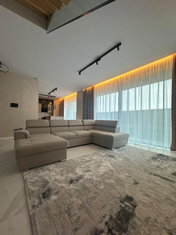 a living room with a sectional couch and large windows at Knight Rooms in Voluntari