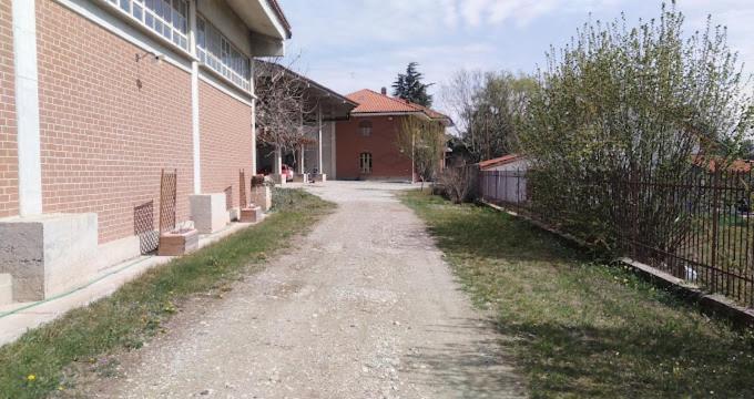 an empty dirt road next to a brick building at La Mandulera in Rivalta di Torino