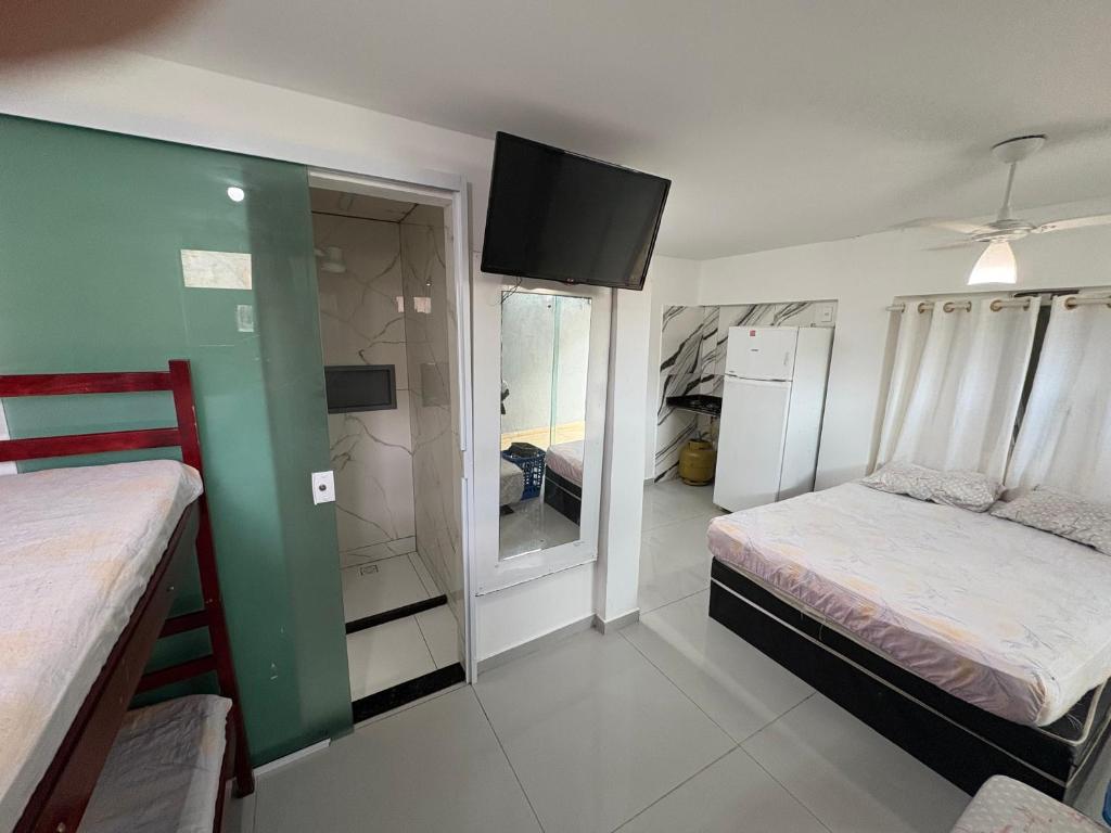 een kamer met twee bedden en een tv aan de muur bij Kitnet em Cabo Frio 02 in Cabo Frio