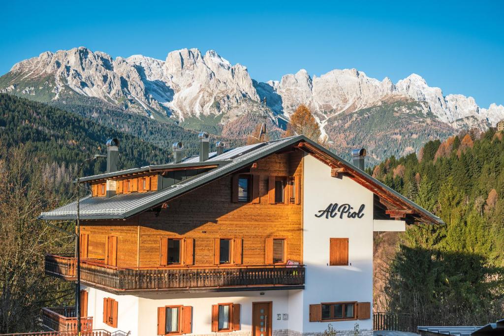 a large wooden house with mountains in the background at Al Piol in San Nicolò di Comelico
