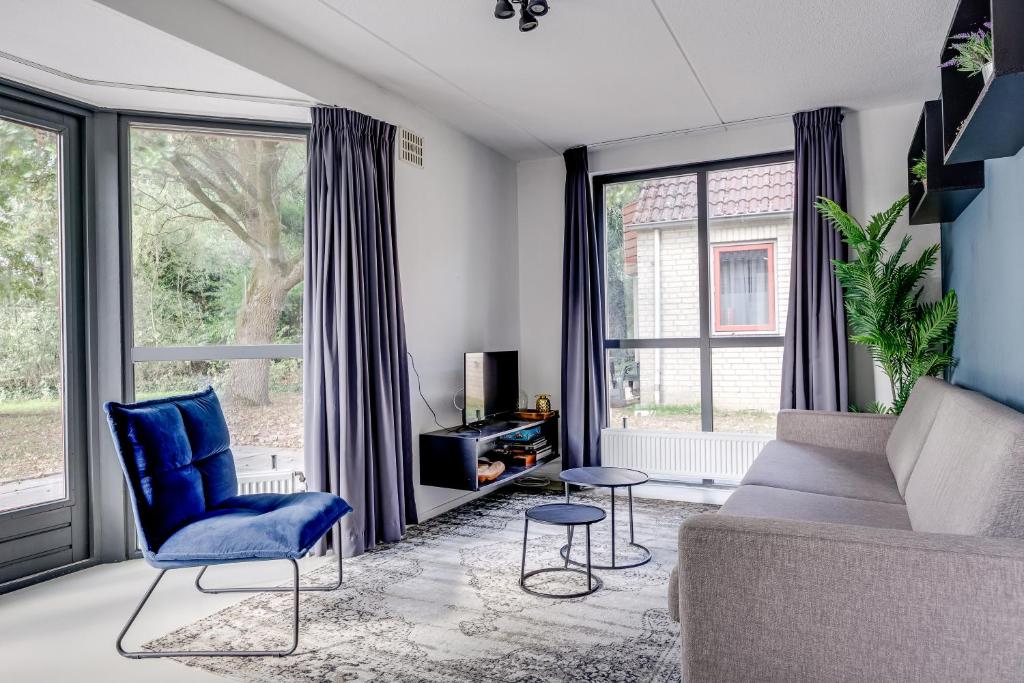 a living room with a blue chair and a couch at 6 - Persons Lakeside 61 Bungalow in Ewijk